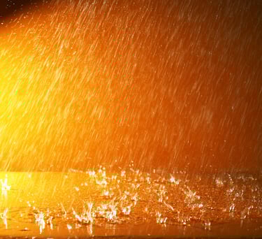 imagem de fundo alaranjado, sugerindo a noite, da chuva caindo sobre uma superfície pintada