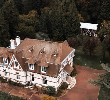 Une maison normande vue du ciel dans un parc boisé