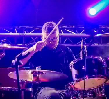Arthur le batteur jouant de la batterie au festival du petit wood éclairé par des spots bleu.