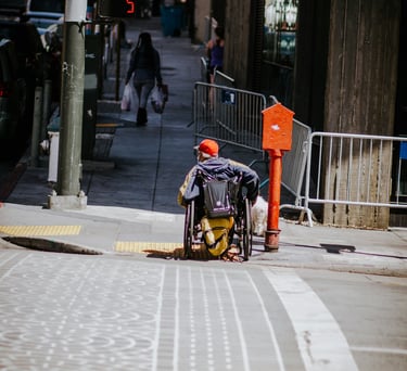eine Person im Rollstuhl auf einer Stadtstraße