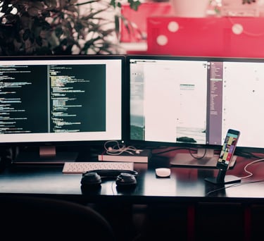a desk with two monitors and a keyboard