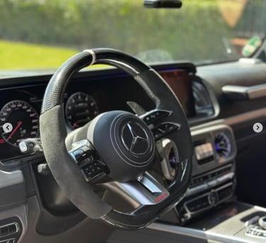 Mercedes-Benz AMG custom carbon fiber and alcantara steering wheel inside a luxury car interior.