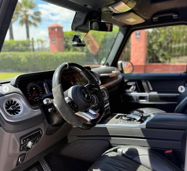 Luxury interior of a Mercedes-Benz G-Class with black leather seats and digital dashboard.