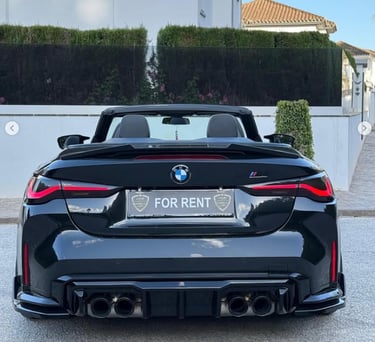 Rear view of a black BMW convertible luxury car for rent with quad exhaust and sporty diffuser.