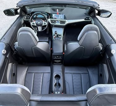 High-angle view of a luxury BMW convertible interior featuring black leather seats and modern dashboard.