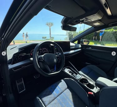 Interior view of a modern Volkswagen Golf R cockpit with digital display and blue stitching.