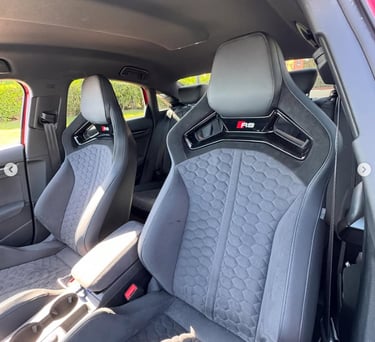 Audi RS sports seats with black honeycomb stitching and Alcantara upholstery in a luxury car interior.