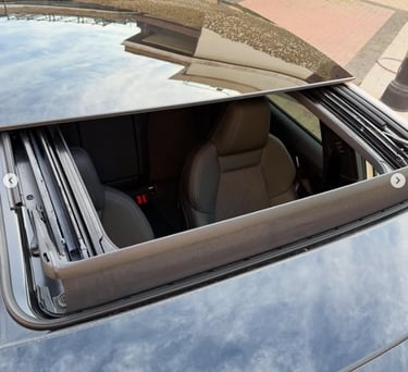 Top view of a luxury car with an open panoramic sunroof showing the black leather interior.