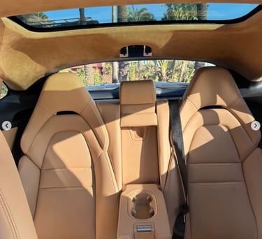 Luxury tan leather car interior showing rear bucket seats and panoramic sunroof.