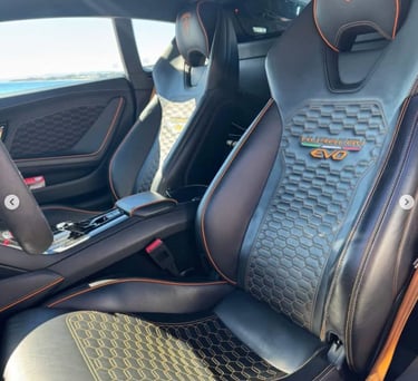 Luxury interior of a Lamborghini Huracan EVO featuring black leather seats with orange stitching.