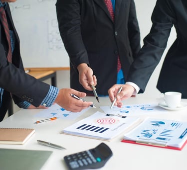 Business team in suits pointing at data charts and target goals during a corporate strategy meeting.