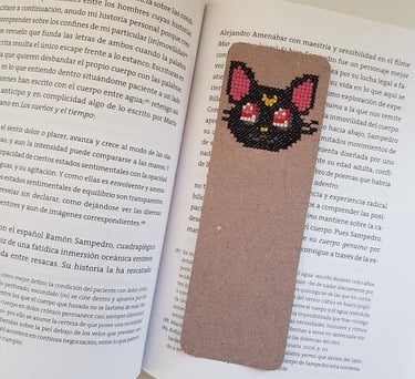 Un separador de libro bordado a mano en punto de cruz sobre un libro