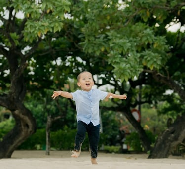 Young boy running joyfully along the beach during a family session at Nusa Dua Beach Bali