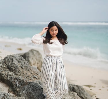 Young girl standing on rocks by the beach at Karma Kandara Bali  