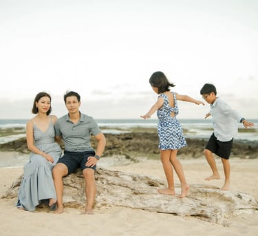 Family sharing playful moments on coastal rocks during a family photography session at The Ritz-Carlton Bali.