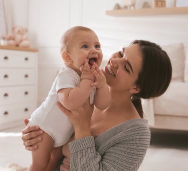 Anne kucağında gülümseyen bebek – evde bebek hemşireliği hizmeti