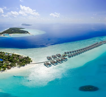 Aerial view of luxury overwater villas and tropical islands in the Maldives surrounded by turquoise ocean waters