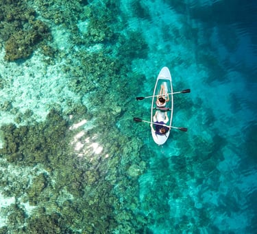 Couple kayaking in crystal-clear turquoise waters over coral reefs in the Maldives – perfect tropical adventure