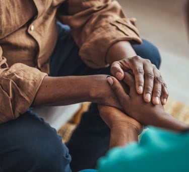 Mãos de duas pessoas se tocando em um gesto de empatia e apoio, em um consultório de psicologia.