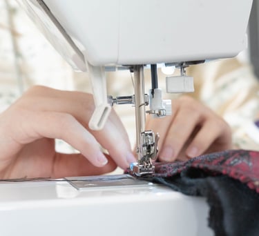 Gros plan sur des mains guidant un tissu sur une machine à coudre