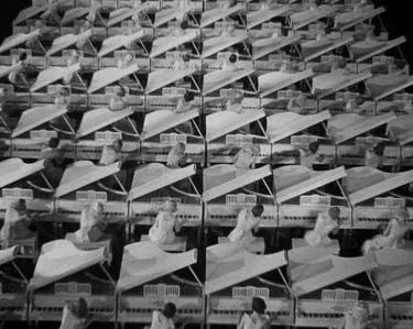 White‑costumed women at white pianos in a black‑background set, resembling a dreamlike rehearsal hal