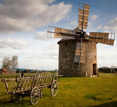 Molino de viento de piedra rústico y carreta agrícola de madera vintage en un campo rural