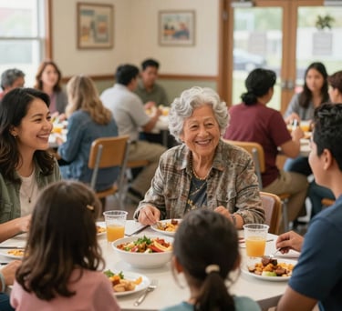 A diverse group of North American / US community members, including a family with children and an elderly woman, sharing a meal or participating in a community gathering in a bright, welcoming community center. They are engaged in conversation and smiling, conveying a sense of connection and support. Warm, inviting indoor lighting creates a sense of comfort and togetherness. The composition is a medium shot capturing several individuals interacting. The style is uplifting, genuine, and emphasizes community and well-being.