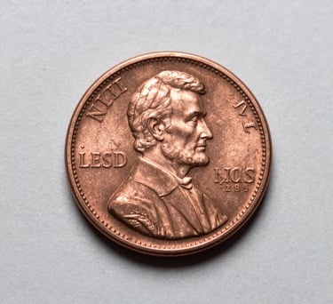 A macro photograph of a rare Lincoln penny showing incredible detail and copper luster, resting on a clean light grey surface. North American / US context.