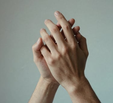 A close-up of two hands clasped together in a gesture of support, set against a background of soft grey and light aqua tones, North American / US context.
