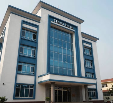 A clean, architectural photograph of the trust's headquarters in Chhotaudepur. The building features modern Indian design with elegant blue accents and large windows reflecting the South Asian sky.
