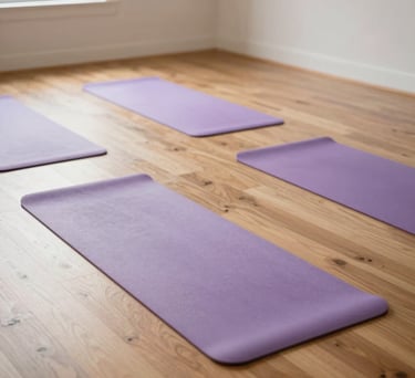 An interior shot of a spacious yoga studio in a North American retreat, with light wood floors and several pale purple yoga mats neatly arranged. Bright natural light fills the room.