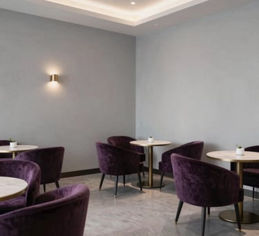 A sophisticated tea lounge in a North American spiritual center with dark purple velvet chairs, light gray walls, and elegant minimalist decor.