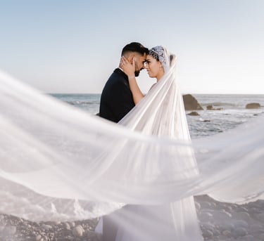 a bride and groom standing on a beach