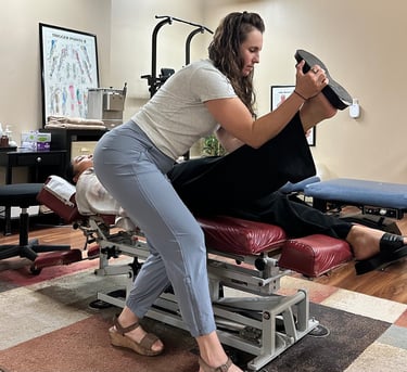 Chiropractor performing nerve tension test on patient laying face up on chiro table.