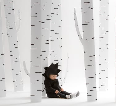 Fashion photography - a baby in a dinosaur outfit with trees