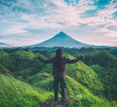 une personne debout sur une colline avec une montagne en arrière-plan