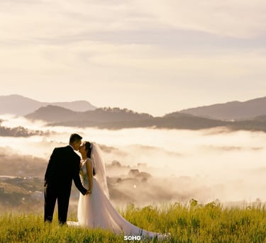 a bride and groom standing on a hill overlooking a valley
