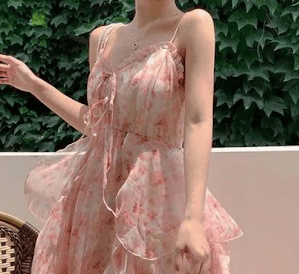 A woman wearing a light, flowy dress with small pink flowers and many large flowy layers.