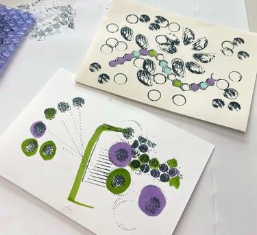 Paper zines with handmade stamps and ink outlines of shapes such as buttons and nut shells.