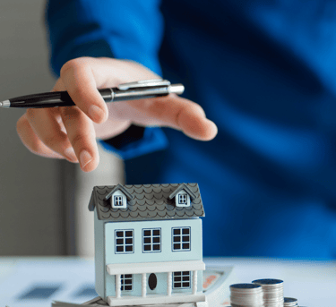 Estimation immobilière d'une maison. Le conseiller immobilier porte une chemise bleue et a un stylo.
