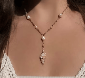 A gold necklace with pearls and a simple shell pendant.