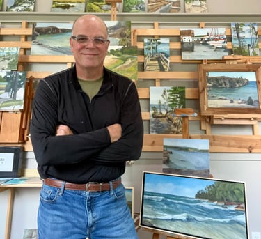 Gary McCaslin standing in front of a wall of paintings