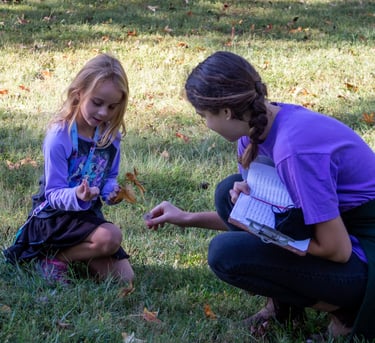 Teacher with one of our youth students outside, picking up natural pieces for an art project.