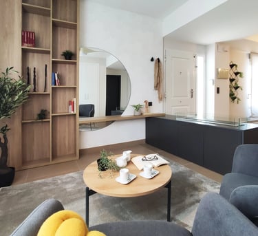 Decoración de interiores de zona relax con librería de madera, chimenea de bioetanol y butaca en San Antonio de Benaguér