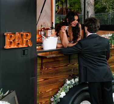 a bride and groom standing in front of our mobile trailer bar