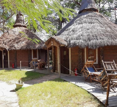 A picturesque view of the Mandina River Lodge, showcasing elegant thatched-roof buildings nestled al