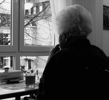image en noir et blanc, une vieille femme regarde par la fenêtre