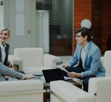 Professional business consultants in a corporate lounge discussing financial strategy documents.