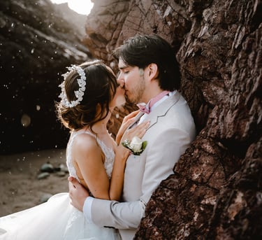 a bride and groom kissing in front of a rock wall