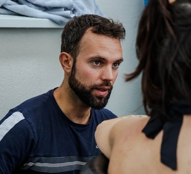 A bearded man looks intently at a woman sitting in an outdoor cold plunge ice bath.